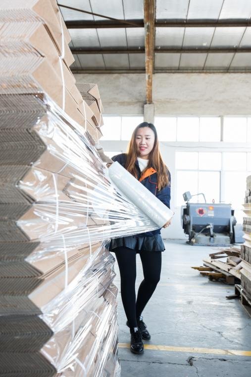 Worker manually stretch-wrapping a palletized load
